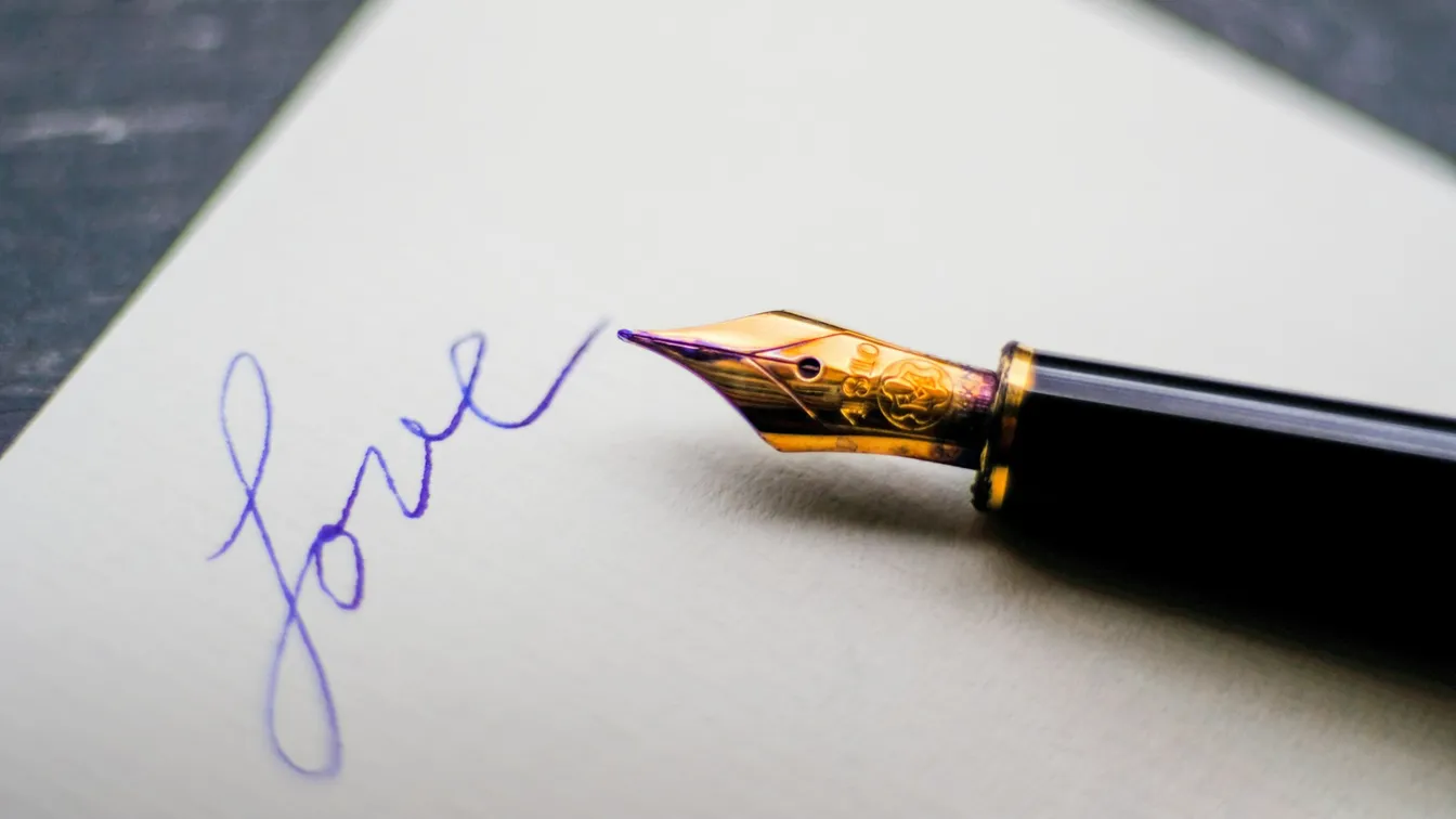 a fountain pen writing love on a piece of paper