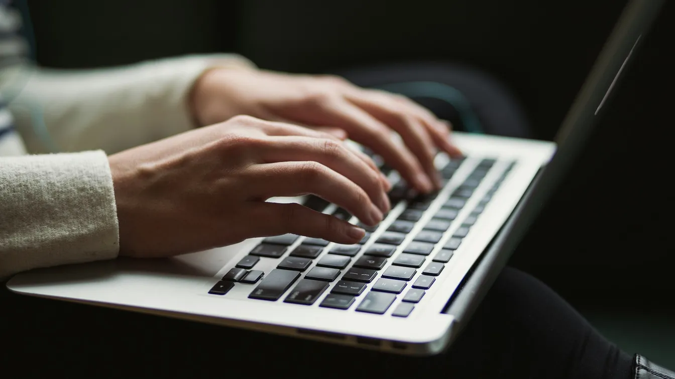 a person's hands typing on a laptop computer