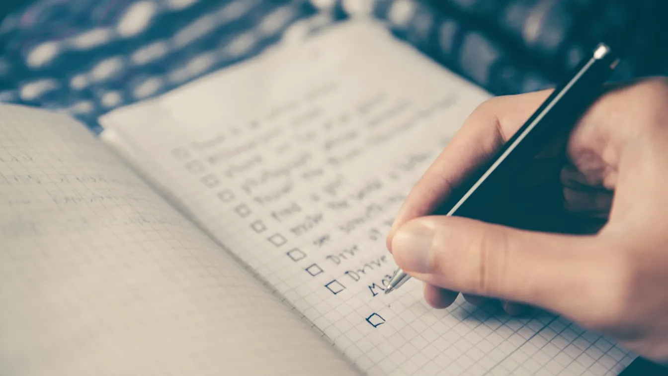 a person writing on a notebook with a pen