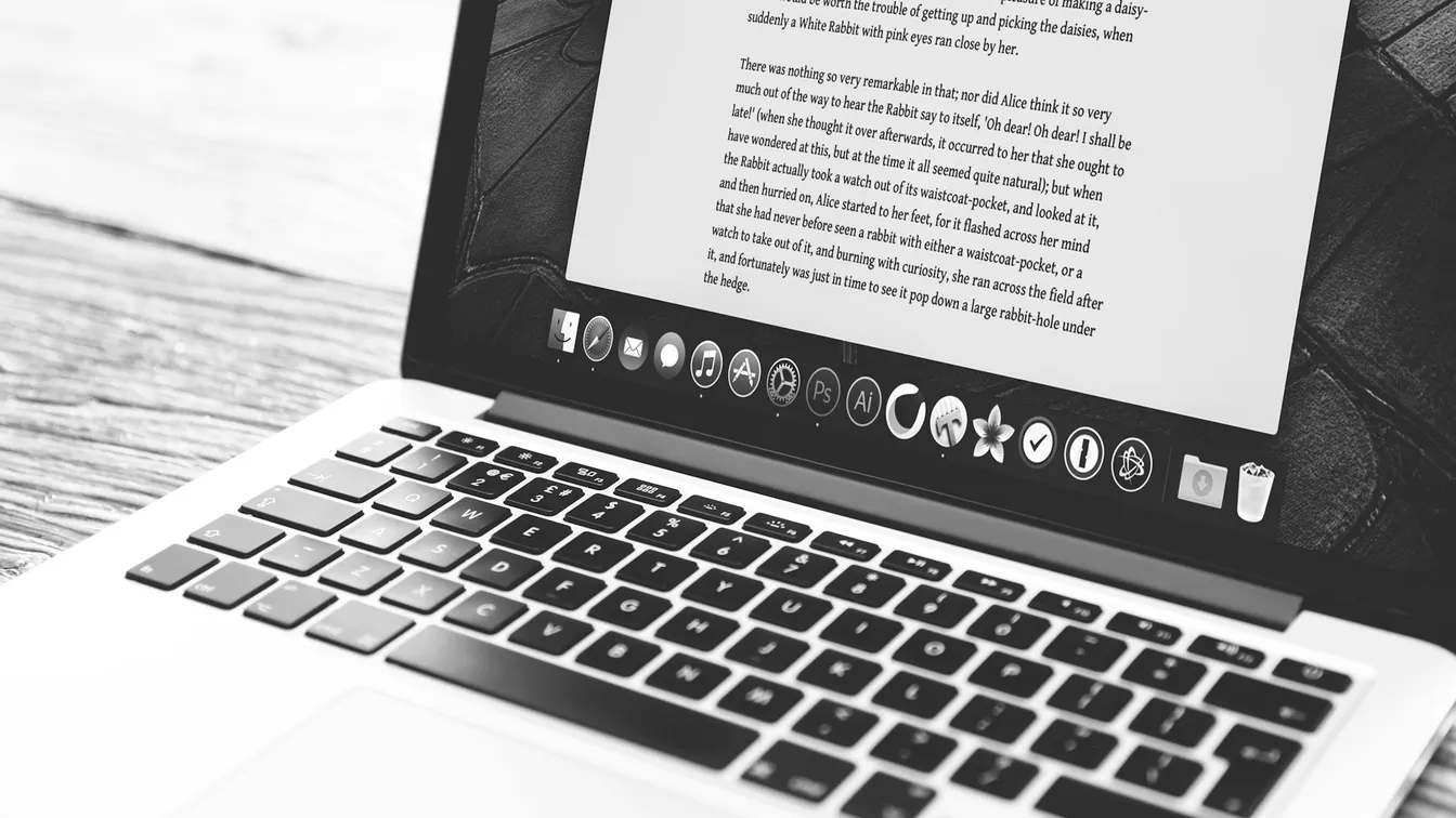 a black and white photo of a laptop on a wooden table