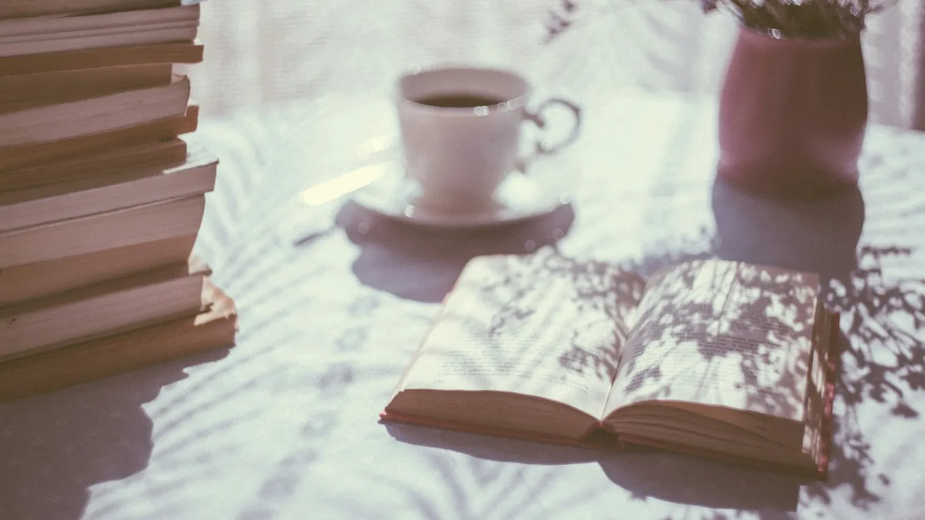 a stack of books on a table next to a cup of coffee