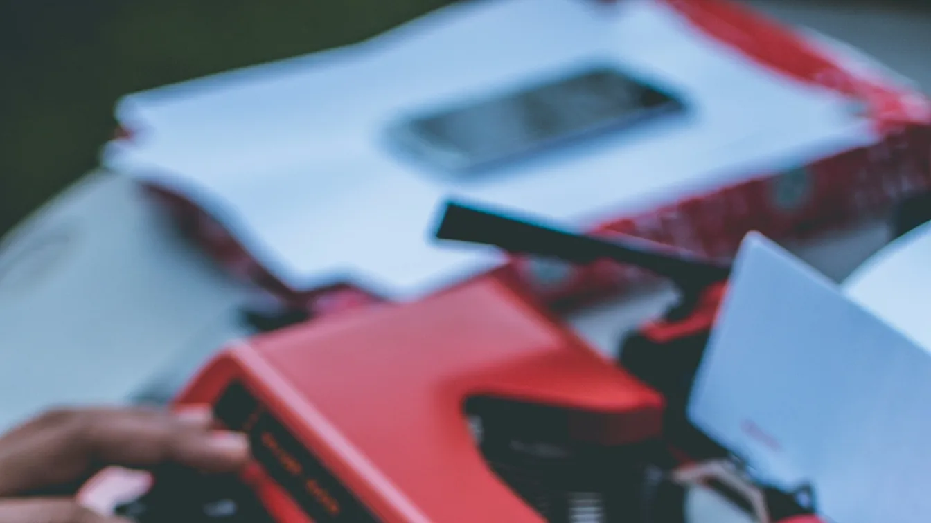 a person typing on a red typewriter