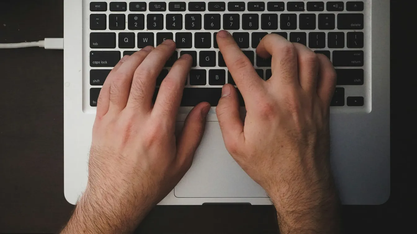 a person's hands typing on a laptop keyboard