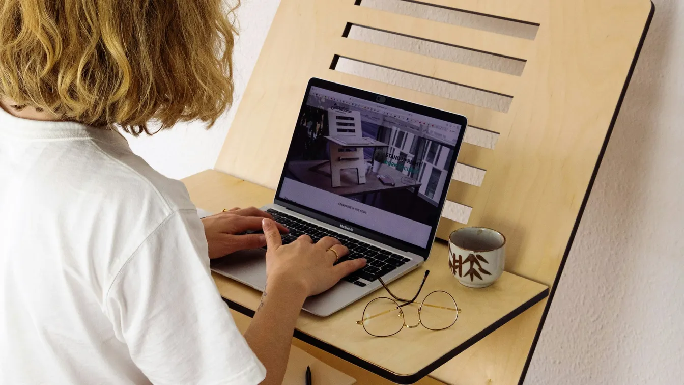 a woman using a laptop on a wooden desk