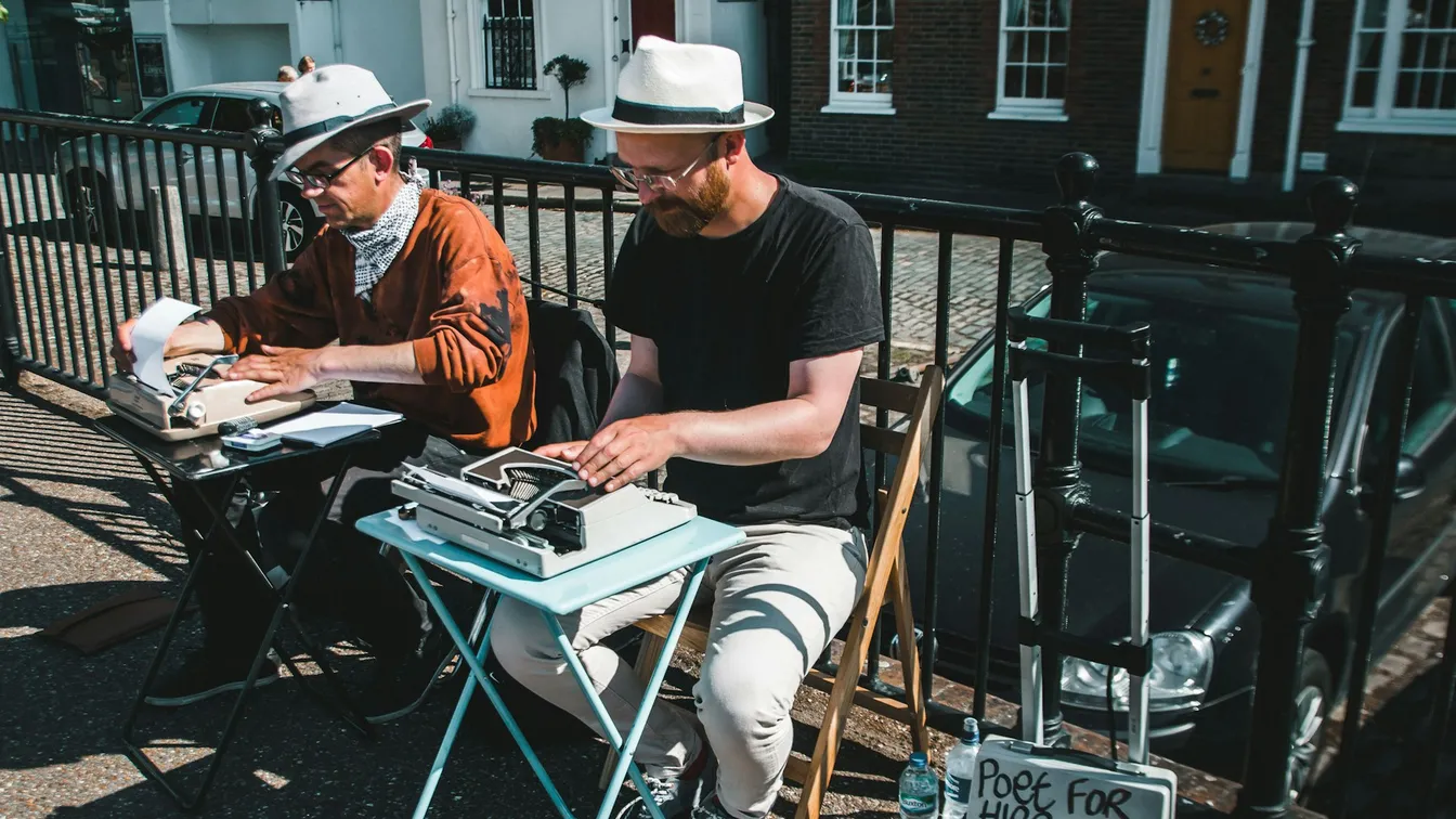 two men in hats working on a typewriter