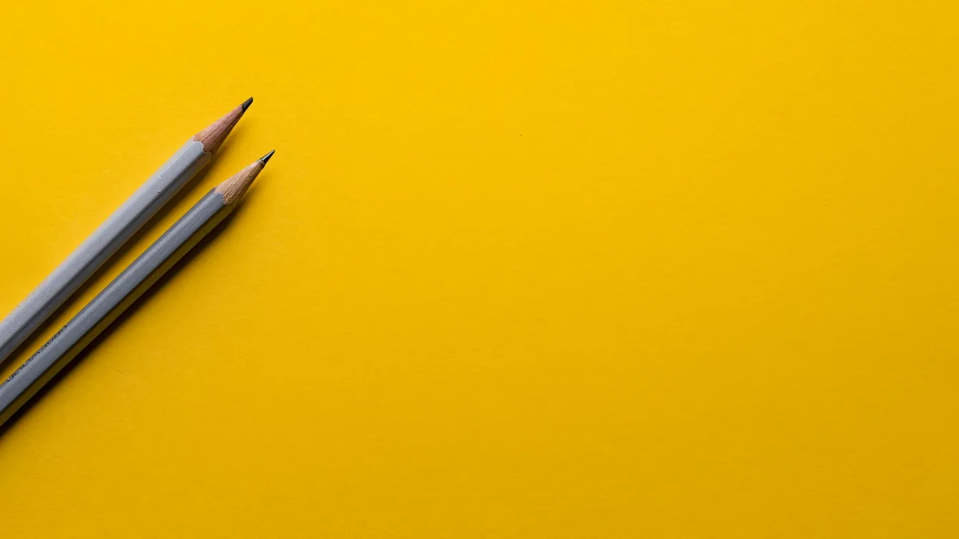 two pencils on a yellow background