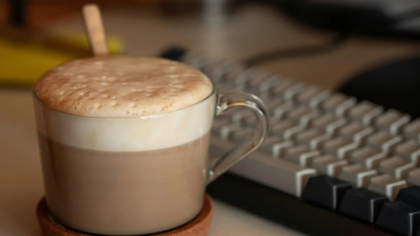 a cup of coffee sitting on top of a keyboard