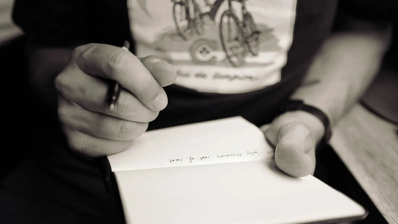 a man writing in a notebook with a pen